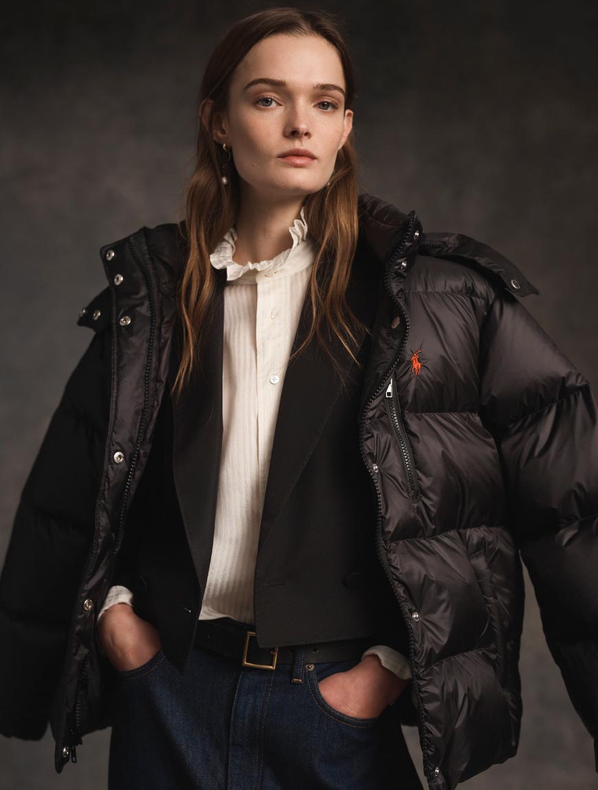 Woman wears a black puffer jacket over a black blazer.