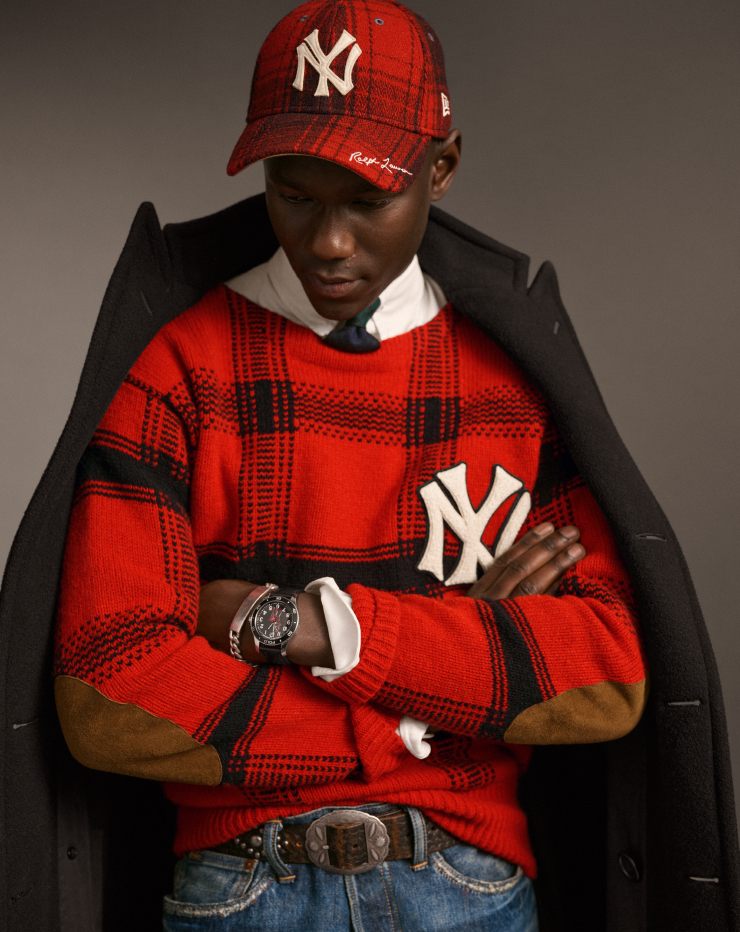 Man wears red plaid Yankees sweater and ball cap.